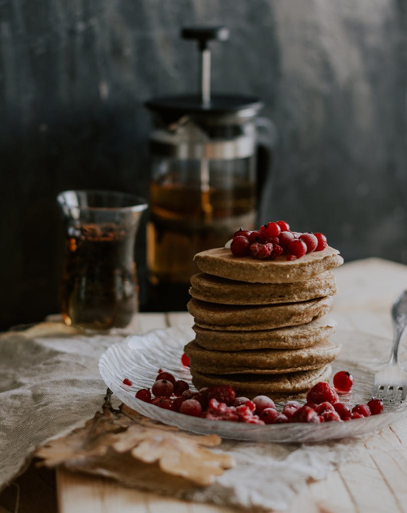Indulge in a rustic breakfast with homemade pancakes topped with fresh berries and coffee.